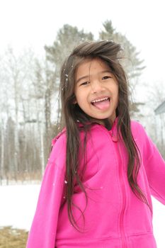 Child sticking out tongue while playing outdoors in winter