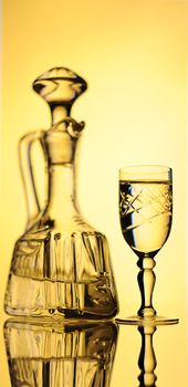 Elegant Crystal Decanter And Wine Glass With Vodka Over Yellow  Background.