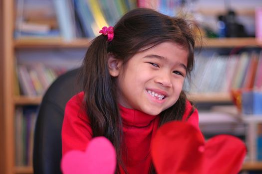 Child holding up two red hearts for valentines