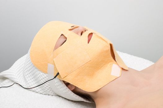 beauty salon, body care series. facial mask electrophoresis procedure applying