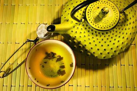 Green asian teapot with cup and green tea