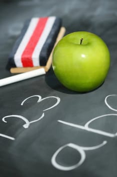 Green apple on chalkboard with easer