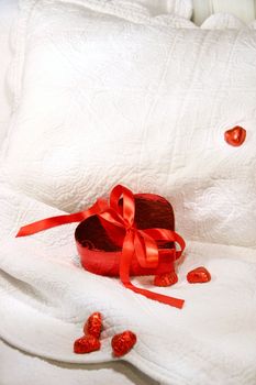 Box of chocolates with red ribbon on a bed for Valentin's day