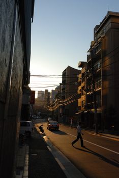 typical Tokyo backyard streets near Roppongi Hills area at evening time with many wires, walking men, cars and motorbike