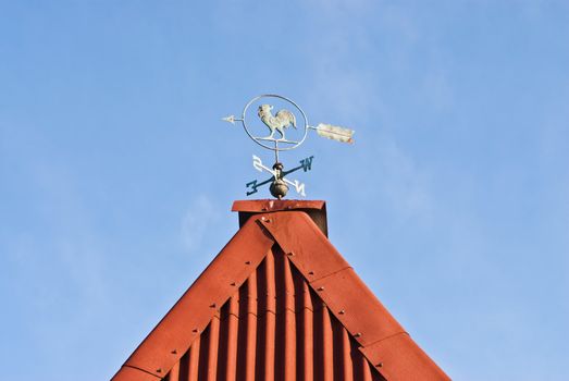 Vane on the roof of a country house on a background of blue sky