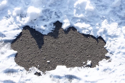 Fragment of the asphalt surface between snowbanks