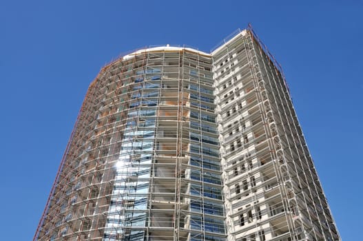 Construction of a new building with blue sky in the background and sun reflection on glass