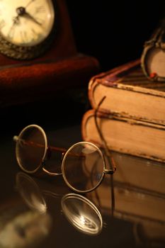 Vintage still life with old spectacles near books and clock