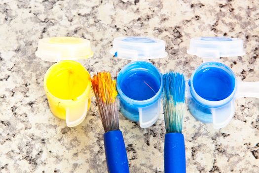 Paint brushes and pots of yellow and blue paint