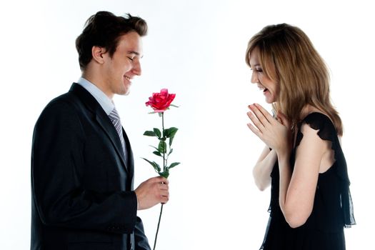 A young man gives a beautiful young woman, a flower in honor of the holiday