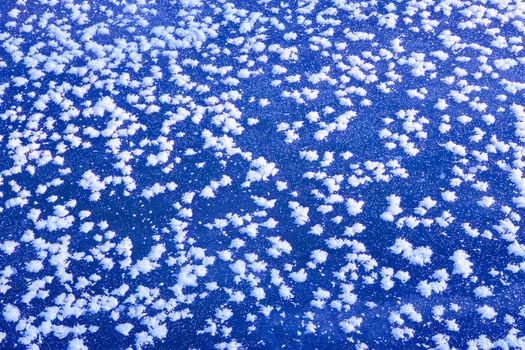 Fragment of frozen surface with the rime in the form of randomly placed snowflakes