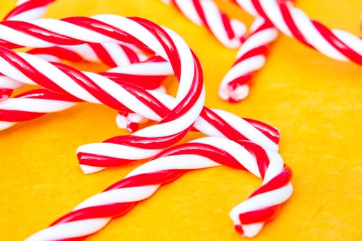 Close up of candy canes lying on a vibrant yellow surface