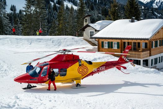 MONTAFON, AUSTRIA - MARCH 16, 2013: A rescue helicopter is ready to evacuate a skier after a heavy accident in Montafon, Austria on March 16, 2013. Skiing safety is becoming more and more of an issue due to crowded slopes and skis becoming faster and faster.