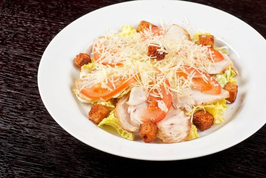 Salad of lettuce, chinese cabbage, tomato, garlic rusk, parmesan cheese, sauce and chicken meat