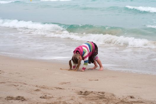 Little girl playing on the beach, sea nad sand