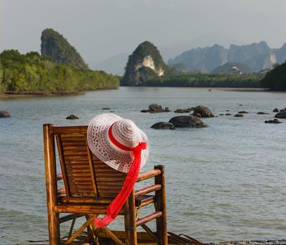 Hat hangs on a wicker chair on the background of the sea