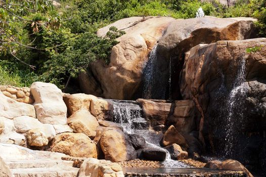 Waterfall in the garden with stones and trees