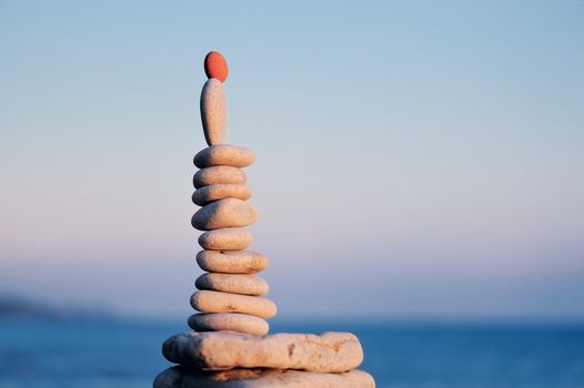 Balancing red stone on the top of pile of pebbles