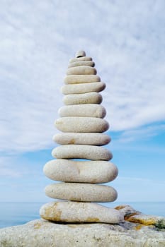 Balancing white pebbles with cloudy sky background