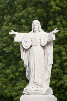 Selective focus on the marble statue of Jesus Christ with tree in the background