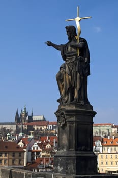 Statue on Charles Bridge on the background of the Prague Castle , Prague , Czech republic