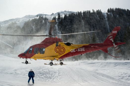 MONTAFON, AUSTRIA - MARCH 16, 2013: A rescue helicopter is ready to evacuate a skier after a heavy accident in Montafon, Austria on March 16, 2013. Skiing safety is becoming more and more of an issue due to crowded slopes and skis becoming faster and faster.