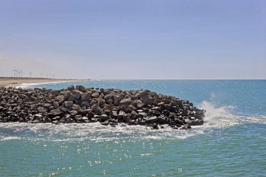 Dwarka Roadtrip. Landscape of the Dwarka coastline in Gujarat India with clean waters, beach and windmill turbines to generate environment friendly power for the local infrastructure. Blue skies reflect of the Arabian Sea with wispy clouds