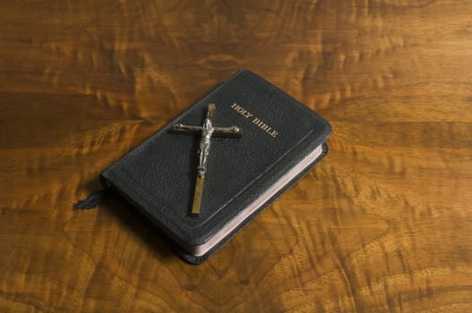 Cross and bible on an antique wood table top.