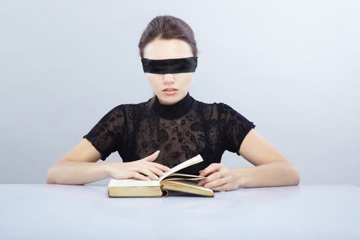 Woman with blindfold reading book indoors