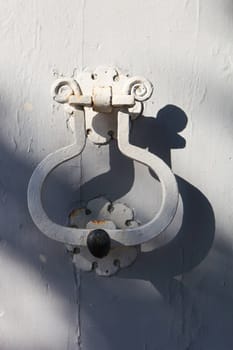 Old white door knocker on a light gray door