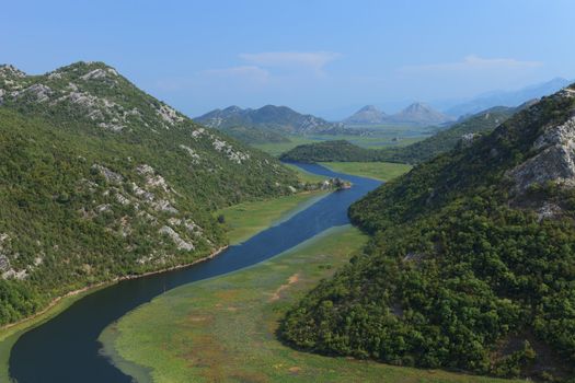 Rijeka Crnojevica river winding through lily pads and mountains in Montenegro