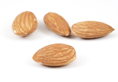 Four almonds on white background with a selective focus on the foreground almond