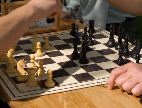 Chess board and hands of people in details 