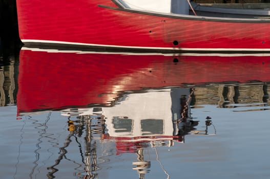 Reflection of a red fishing boat docked at Louisbourg harbor, Nova Scotia