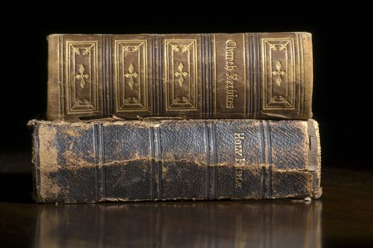 Antique Bible and Church Service books on a old wood table with black background with copy space area