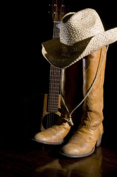 Spotlight on country music symbols, cowboy boots, acoustic guitar and hat
