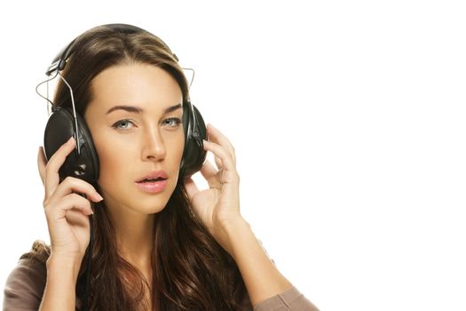 young brunette woman listening to music on white background