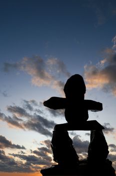 Selective focus on the Inukshuk silhouette in the foreground with sunset in the background