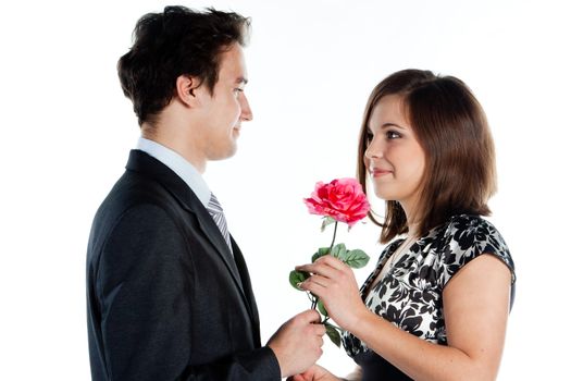 A young man gives a beautiful young woman, a flower in honor of the holiday