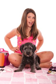 smiling brunette teenage girl in swimsuit at the beach with her shipoo dog (studio setting with beach and personal items) isolated on white background