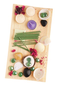 gorgeous spa setting with candles, stones, seashells, sand, incense and dry petal roses on a wooden mat (isolated on white background)