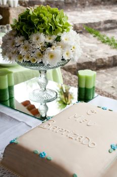 beautiful baptism or christening cake with a gorgeous flowers arrangement and candles (all in green colours)