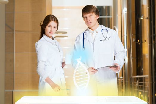 two doctors stand near glowing table discussing. projected objects on a desk