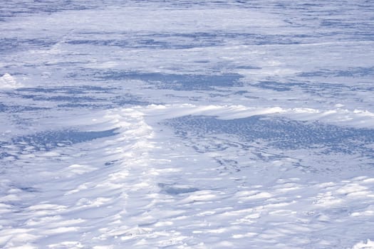 Snow hummocks on the surface of frozen pond