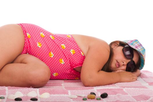 beautiful brunette teenage girl in swimsuit sleeping at the beach (studio setting with towel and pebbles, isolated on white background)