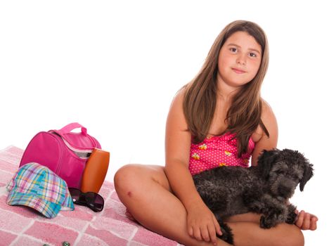 smiling brunette teenage girl in swimsuit at the beach with her shipoo dog (studio setting with beach and personal items) isolated on white background