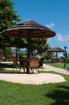 straw umbrella and chairs in a tropical resort (next to the swimming pool)