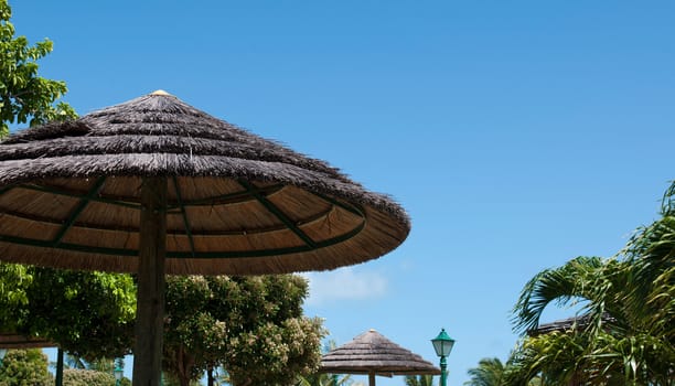 straw umbrella in a tropical resort (gorgeous blue sky for copy-space, summer vacations concept)