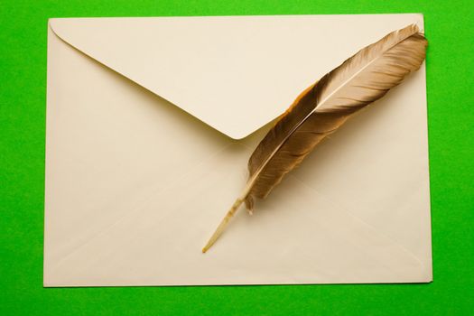 Envelope and feather isolated on green