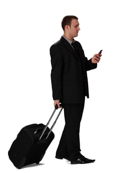 Young businessman with a suitcase reading a phone message against a white background.